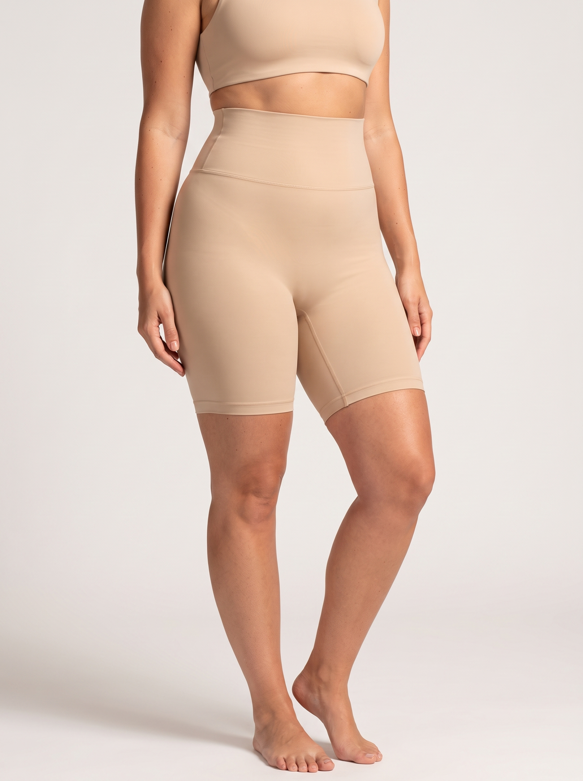 AI-generated model wearing the Everyday Sculpt high-waist mid-thigh shorts in Beige, front three-quarter view