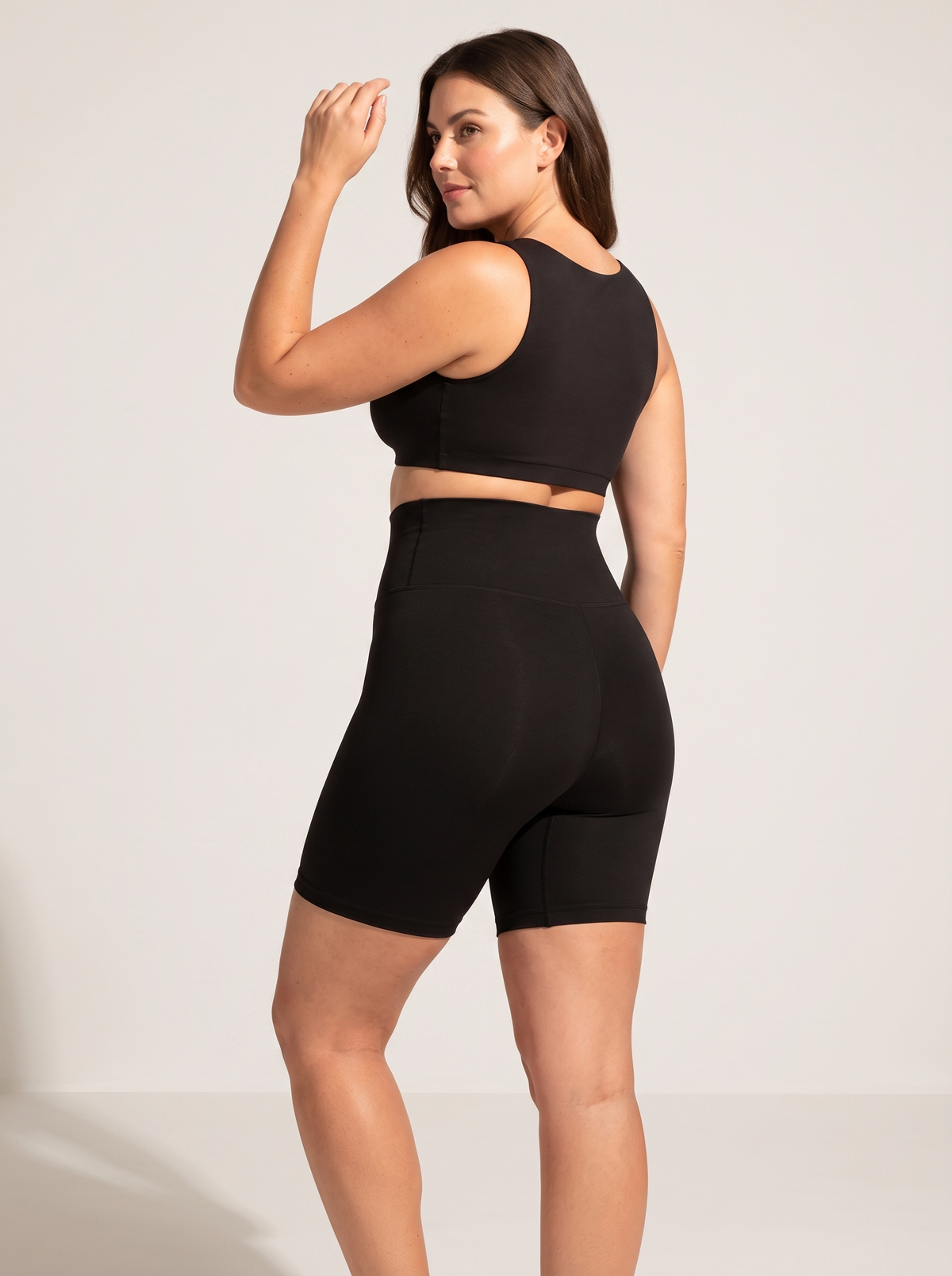 AI-generated model wearing the Everyday Sculpt high-waist mid-thigh shorts in Black, back three-quarter view